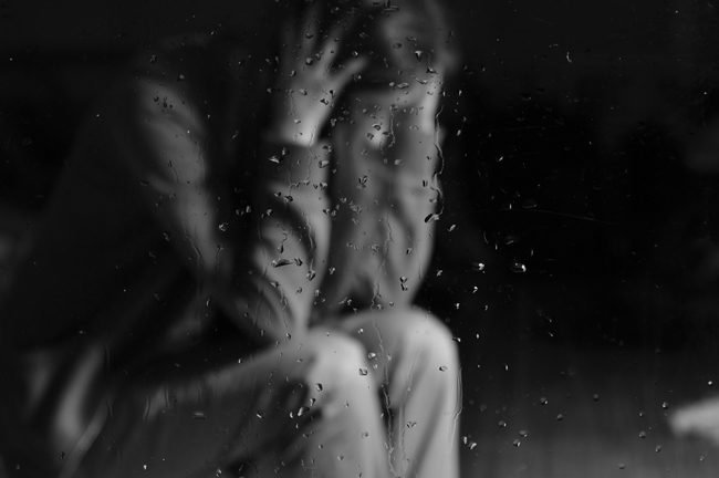 addicted to Demerol, Addiction to Demerol, Abuse of Demerol, upset woman seen through glass with rain on it - black and white