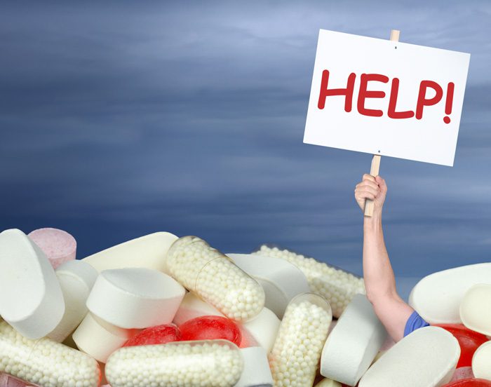 person holding help sign, drowning in pills