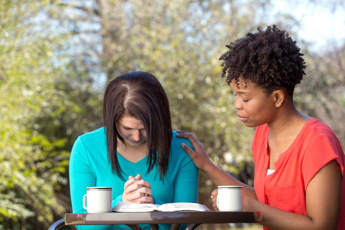 two women at outdoor cafe - talking and praying