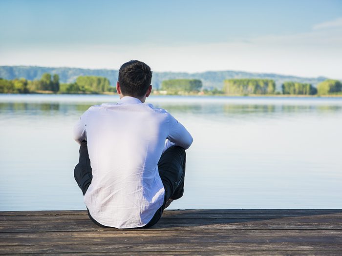 man sitting at the edge of a lake with back to camera