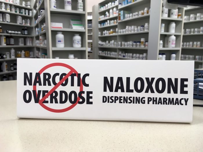 naloxone dispensing pharmacy sign sitting on pharmacy counter