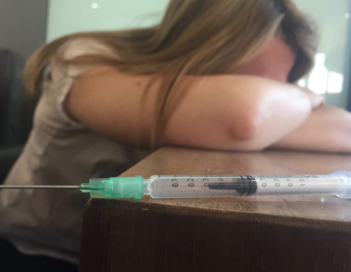 upset woman with syringe nearby