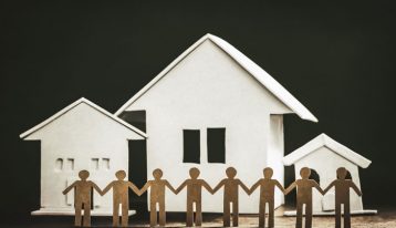 Benefits of Transitional Living After Addiction Treatment, cut outs holding hands, houses