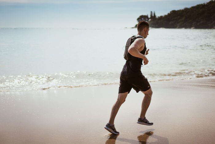 man in black shorts and shirt running on beach - physical