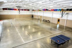 large gymnasium with lightly colored floors and volleyball net set up