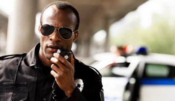High-Risk Professions, African American male police officer using CB radio - work