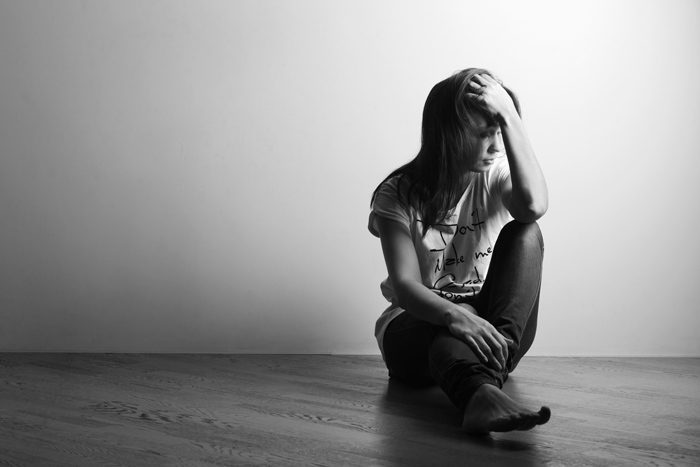 black and white image of young woman sitting on floor - depression and addiction