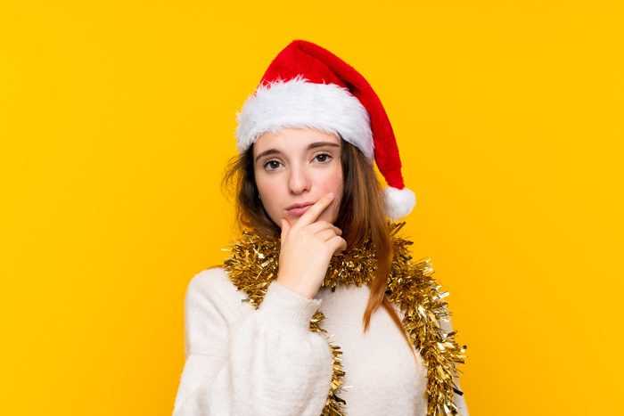 Treatment During the Holidays, young woman in a Santa hat with questioning body language - holidays and addiction