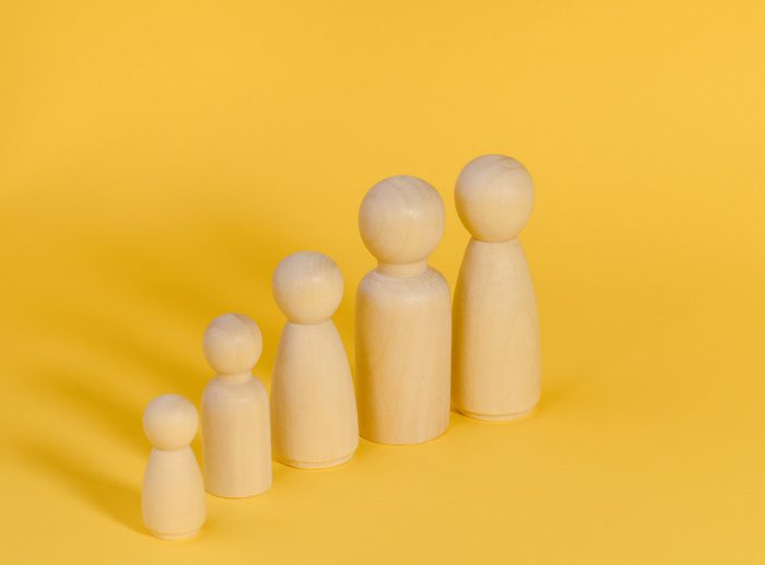 wooden pegs representing family members against yellow background - family systems therapy
