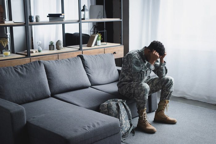 Veteran Addiction Treatment in Texas, Addiction Treatment for Veterans in Texas, veterans’ addiction treatment program, young Black man in military fatigues sitting on couch at home - veterans and addiction